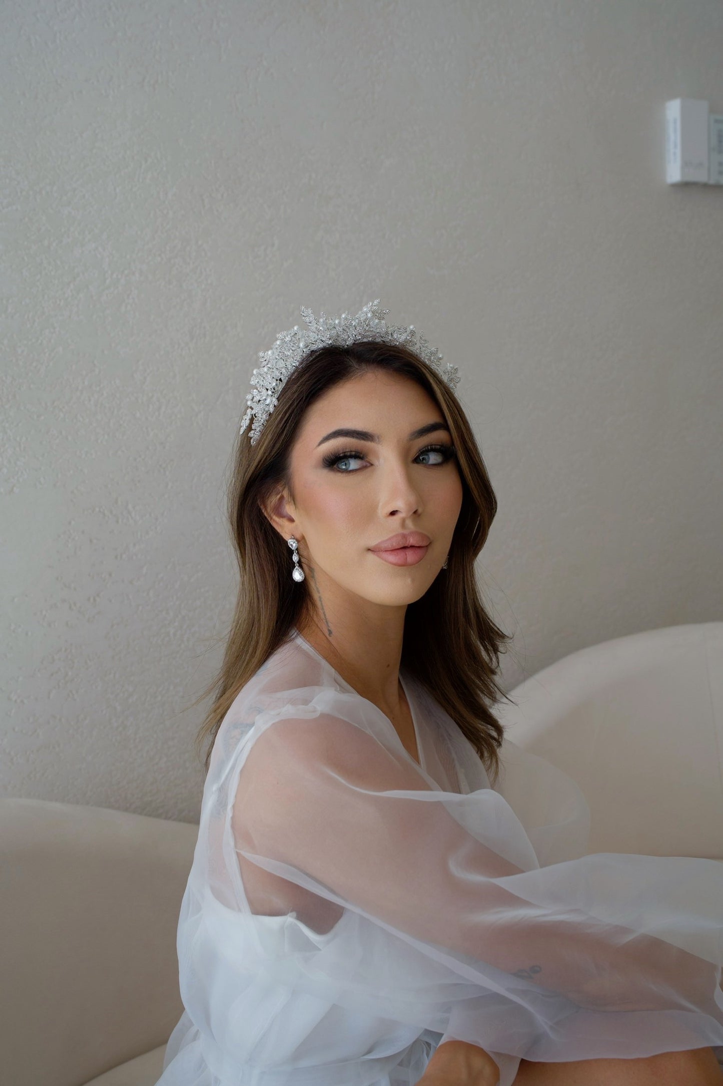 Elegant lady in white dress, tiara, and stylish Iris silver earrings
