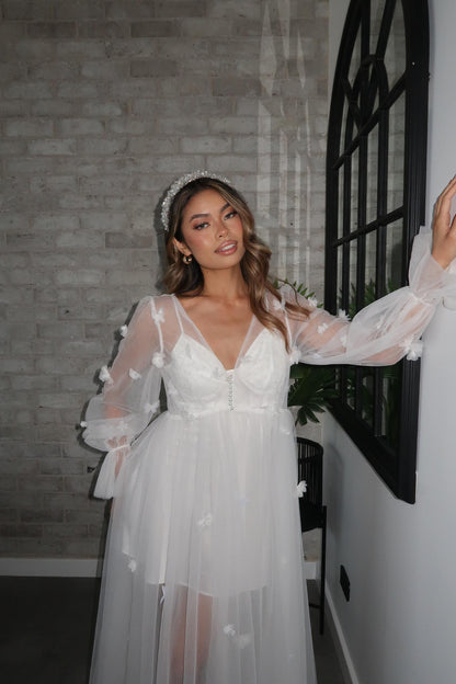 Image of a woman posing for the camera while wearing a tulle robe adorned with butterflies and handmade flowers