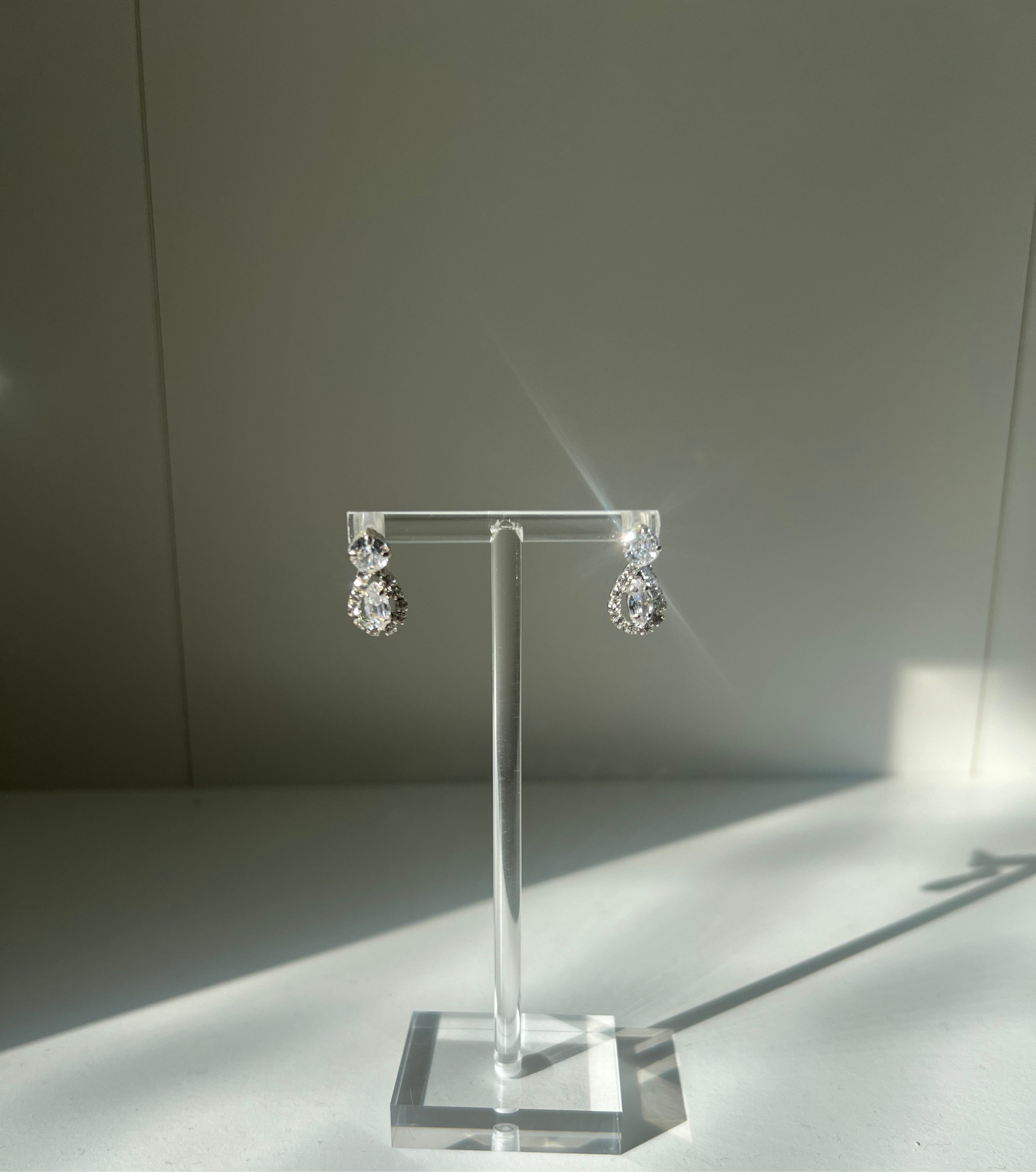 Shiny Imogen diamond earrings displayed on a clear stand