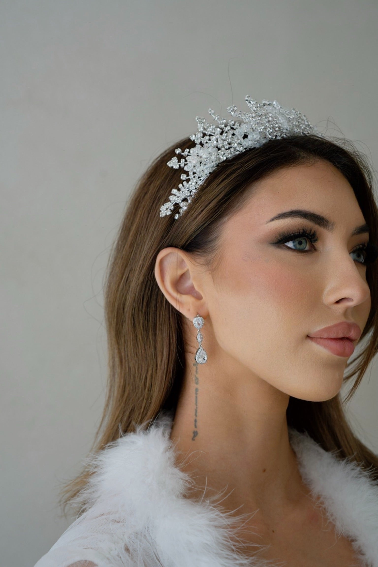 A stylish woman in a white dress and tiara, accessorized with elegant Iris silver earrings