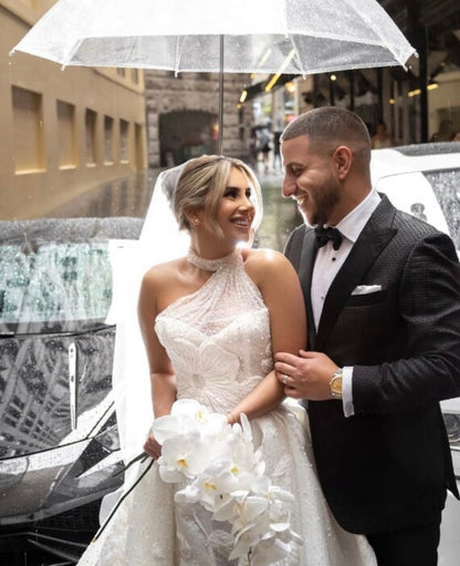 Bride and groom smiling under clear umbrella, happy and in love