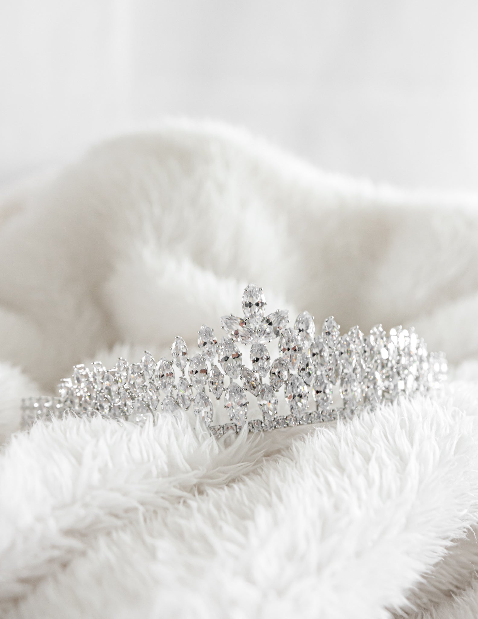 A sparkling diamond tiara resting on a white soft blanket
