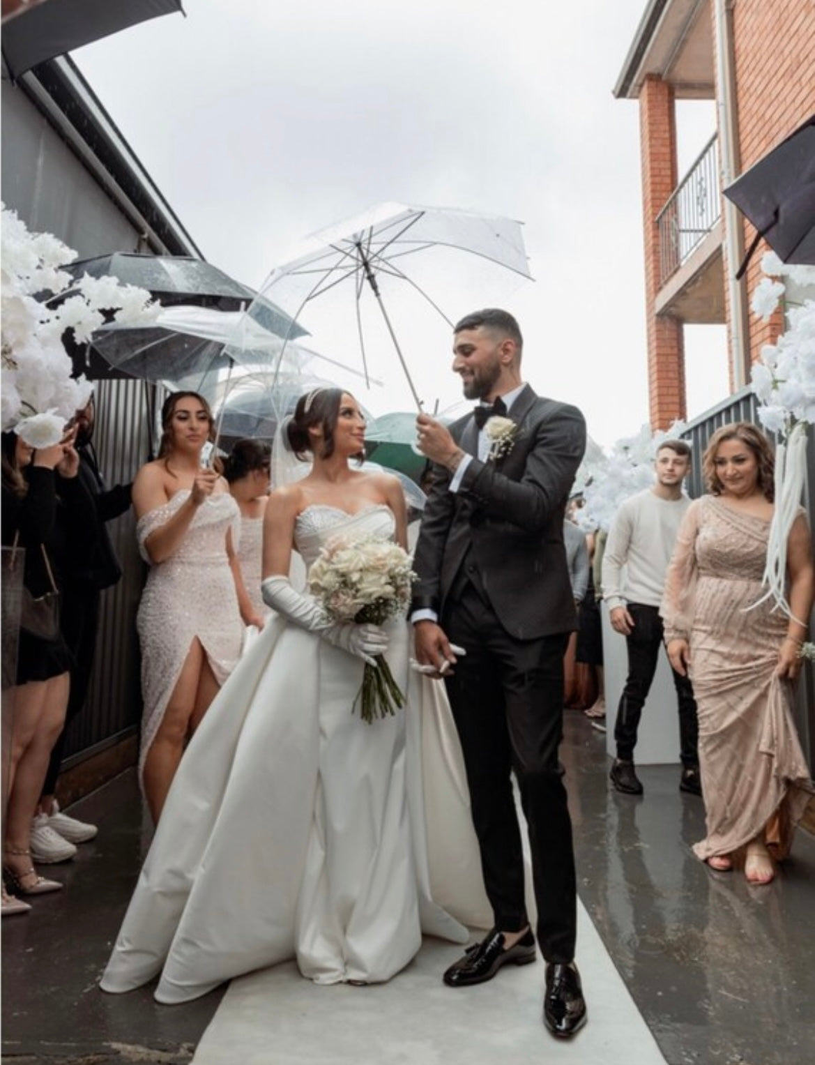 Couple holding hands under clear umbrella at their wedding