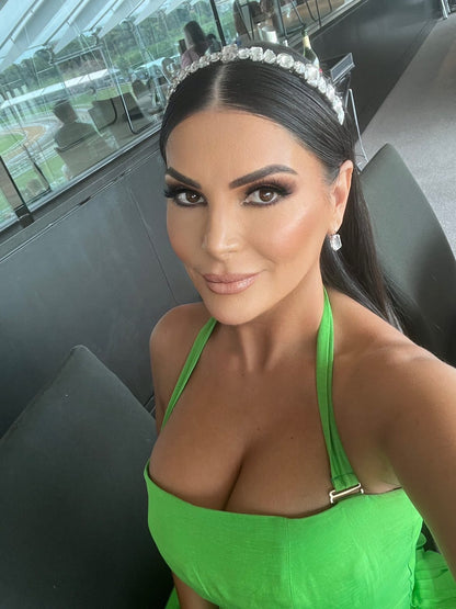 Woman in green dress taking selfie, wearing a stunning diamond headband