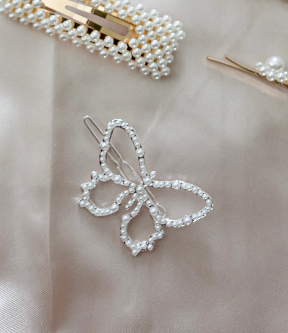 A butterfly hair clip with dazzling pearls on a white surface