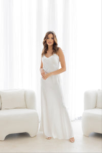 Woman in white bridal long slip standing by white furniture